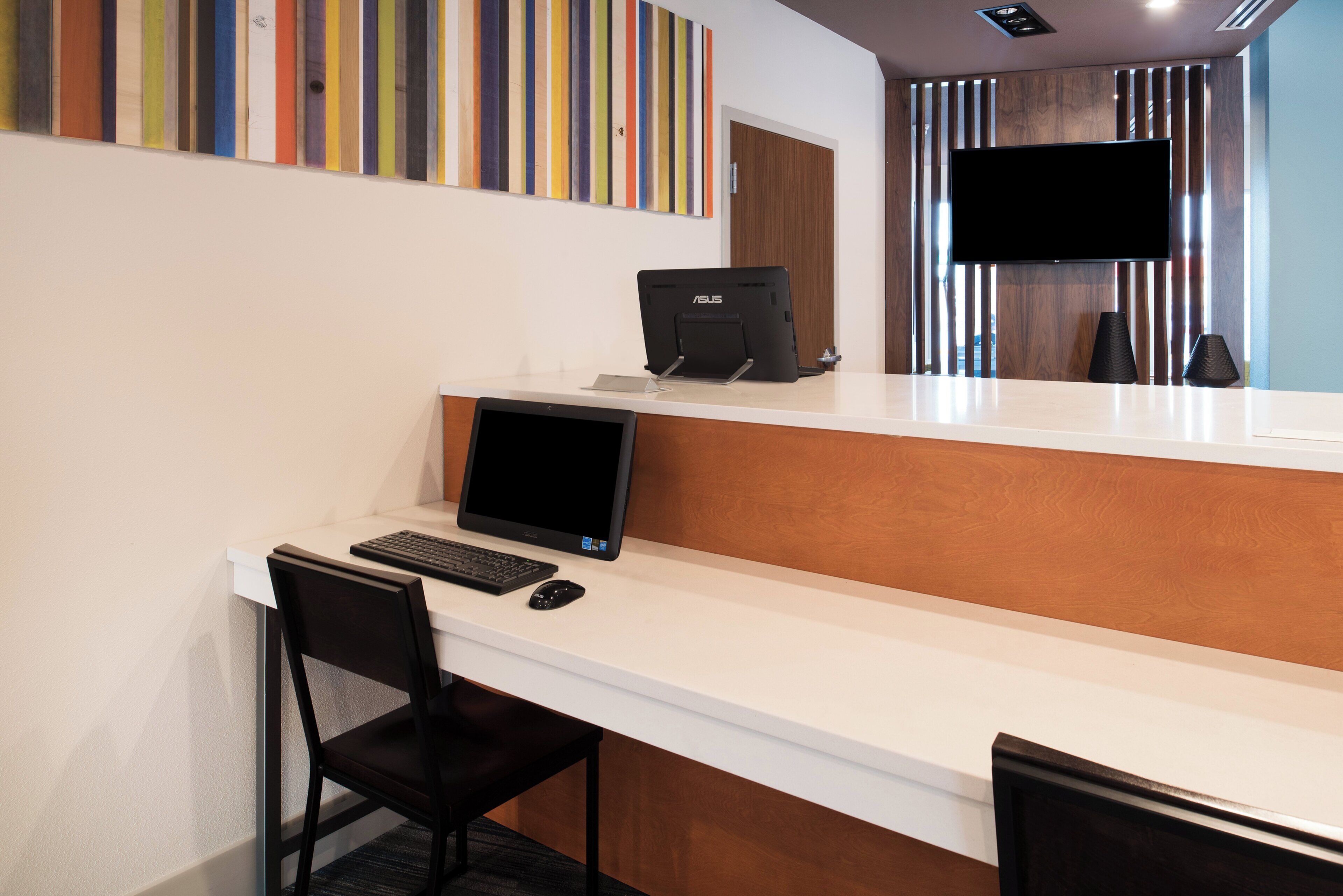 A hotel reception desk with a computer, keyboard, and mouse.
