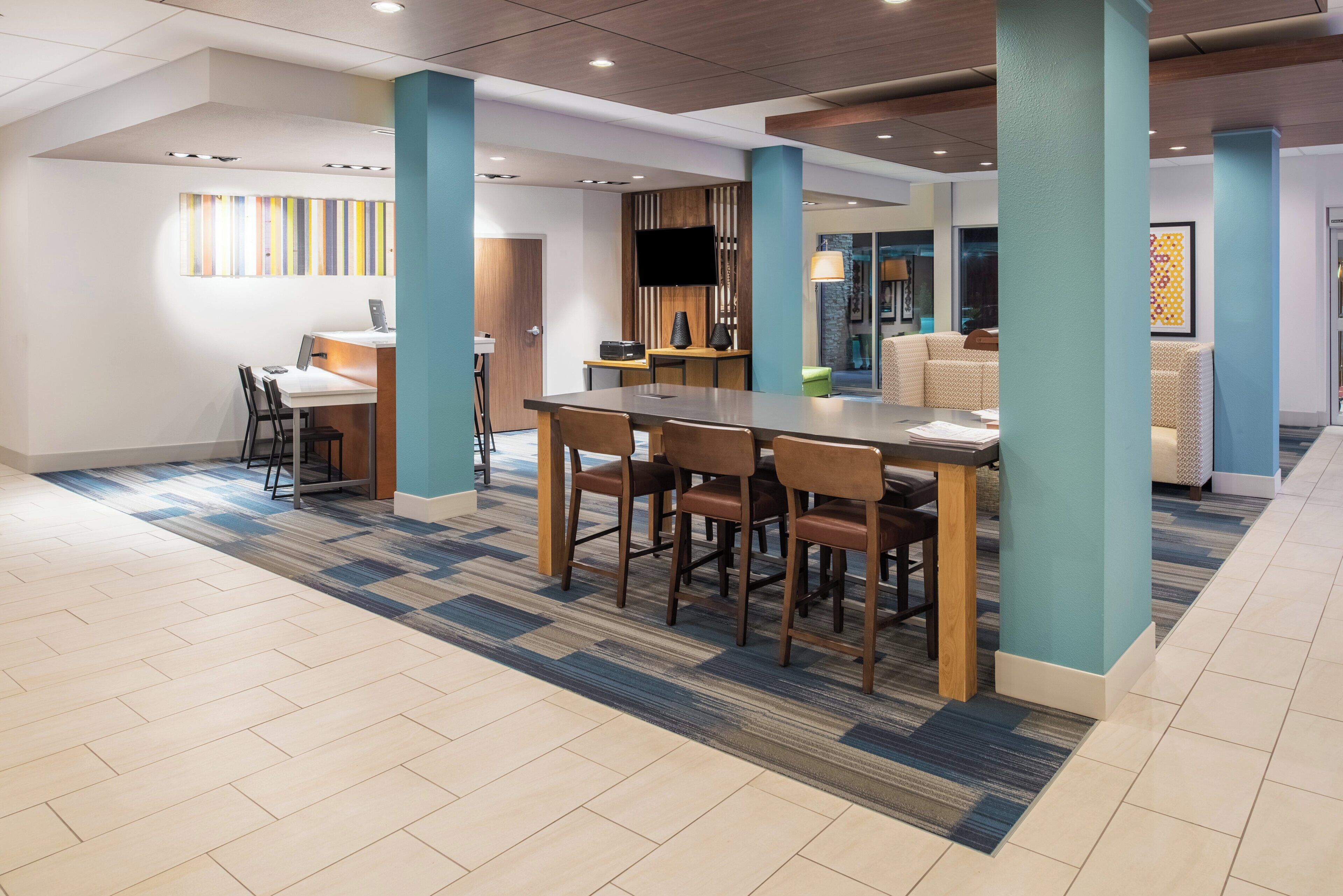 A hotel lobby with a reception desk, seating area, and a television.