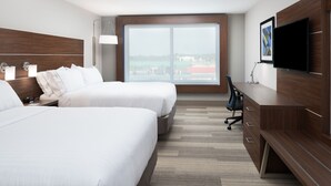 A hotel room with two beds, a desk, a chair, a TV, and a large window with a city view. - Holiday Inn Express & Suites Kingdom City by IHG (Kingdom City)