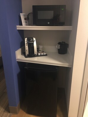 A kitchenette with a microwave, coffee maker, and a small refrigerator.