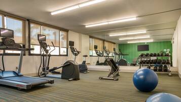 A gym with treadmills, elliptical machines, a stationary bike, and free weights.