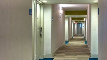 A hotel corridor with carpeted floors, doors, and light fixtures.