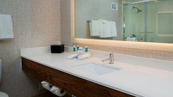 A modern bathroom with a white sink, wooden vanity, and a large mirror.