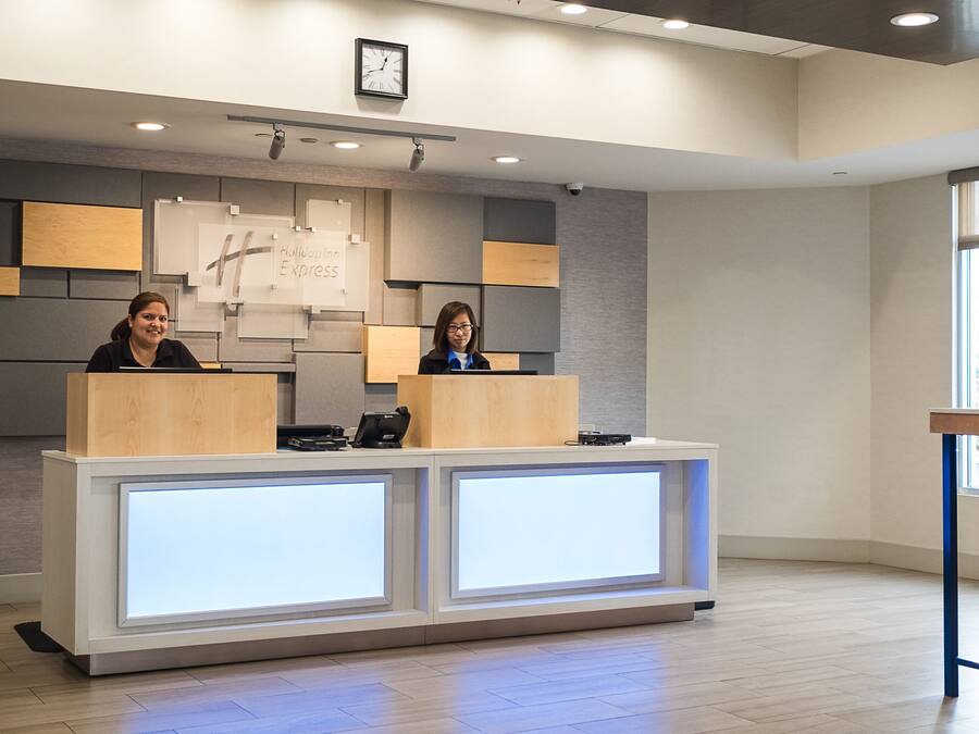 A reception desk with two staff members, a clock, and a sign reading "Holiday Inn Express".
