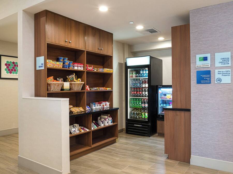 Un hall d’hôtel équipé d’un kiosque en libre-service, d’un distributeur automatique de collations et d’une étagère en bois contenant divers articles.