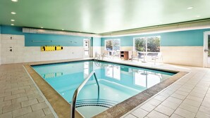 An indoor swimming pool with clear blue water, surrounded by beige and white tiled flooring. - Holiday Inn Express & Suites Detroit Northwest - Livonia by IHG (Livonia)