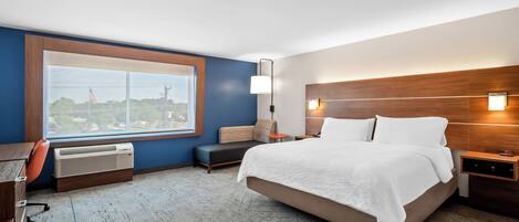 Quarto de hotel moderno com uma cama grande, uma escrivaninha e vista para a cidade.