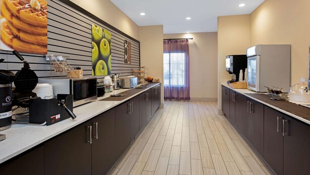 Una cocina moderna con una encimera larga, microondas y cafetera.