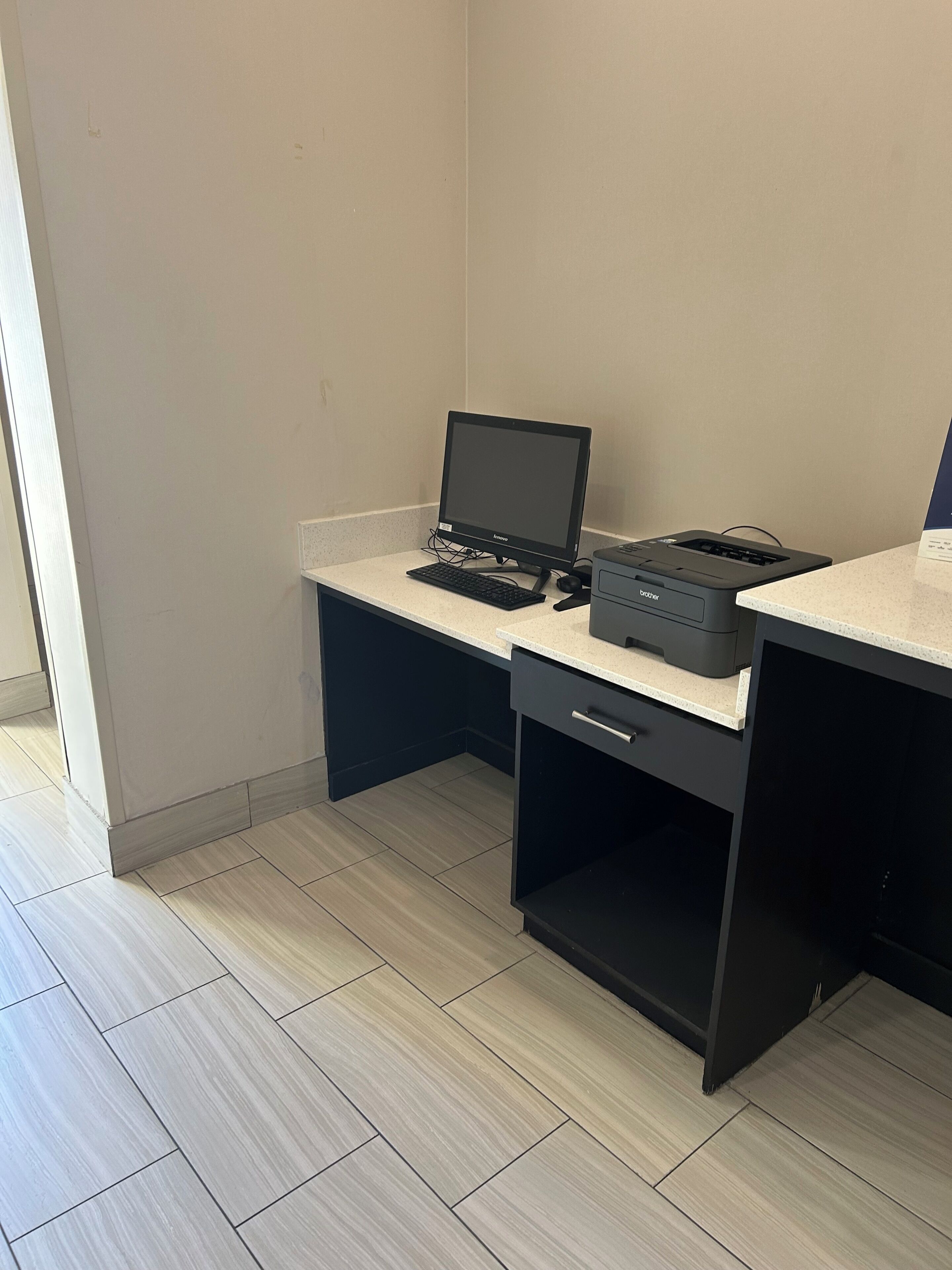 A small office space with a desk, a laptop, a printer, and a drawer unit.