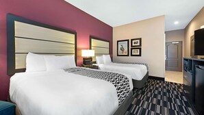 Habitación de hotel con dos camas, televisión y escritorio.