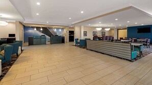 Un vestíbulo amplio con mostrador de recepción, zona de estar y una escalera.