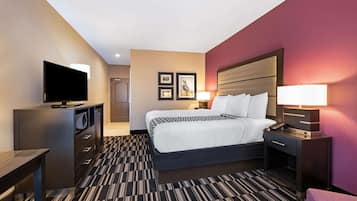 A hotel room with a bed, a TV, a desk, a chair, and a lamp.