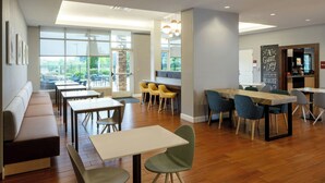 Un espace repas moderne avec un plancher en bois, un long banc et plusieurs tables et chaises.