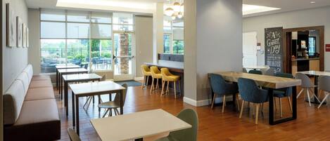 A modern dining area with wooden flooring, a long bench, and several tables and chairs.