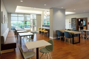 Un comedor moderno con suelo de madera, un banco largo y varias mesas y sillas.
