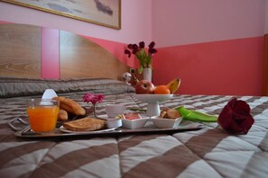 A breakfast tray on a bed with toast, fruit, and a drink.