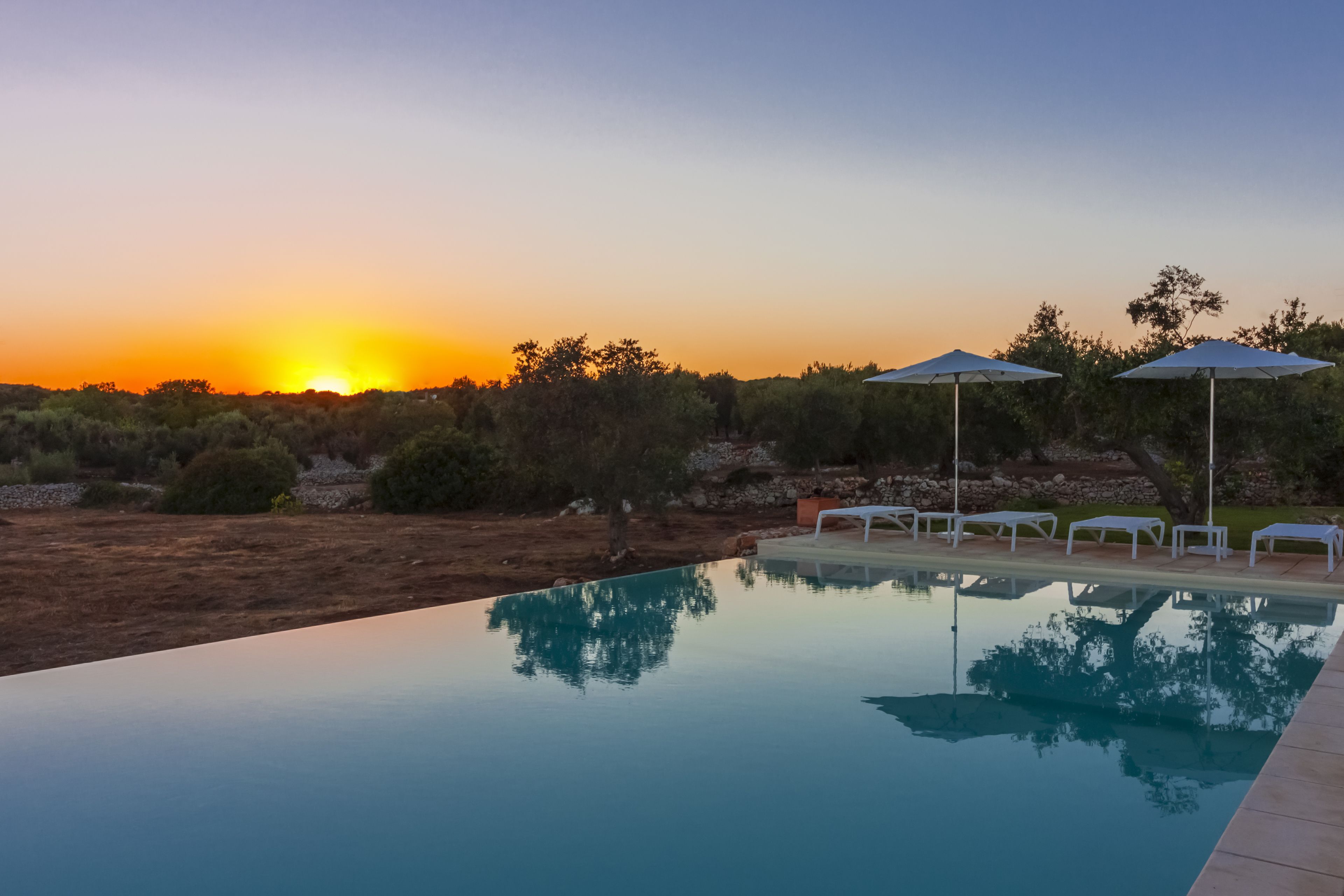 Una piscina al aire libre de temporada, sombrillas, tumbonas