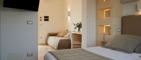 Un dormitorio con cama, escritorio, silla, televisor y lámpara de pared.