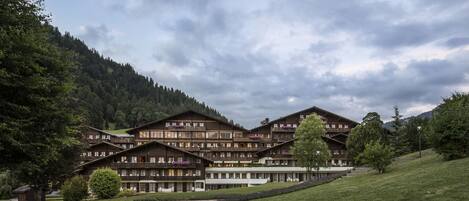 A multi-story hotel with a traditional Alpine architectural style, featuring balconies and a central courtyard.