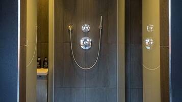 Un área de ducha moderna con puerta de cristal, ducha y panel de control.