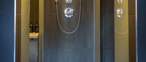 A modern shower area with a glass door, a showerhead, and a control panel.