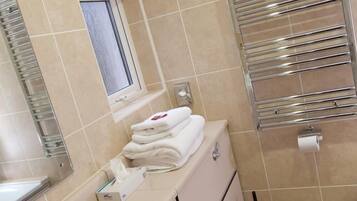 Un baño con lavamanos, espejo, toallero, inodoro y ventana.