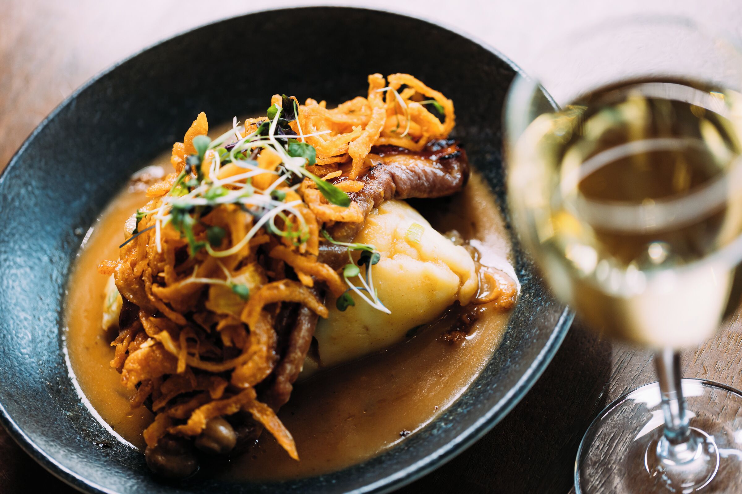 A plate of food with a glass of white wine.