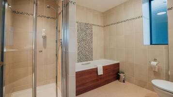 Un baño moderno con cabina de ducha de vidrio, tocador de madera y espejo con marco azul.