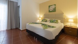Habitación de hotel con cama, dos mesitas de noche, lámpara, un cuadro y una puerta corredera.