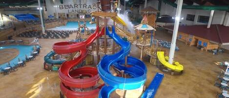 An indoor water park with multiple slides and a stage area.