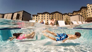 A swimming pool with clear water, lounge chairs, and a hotel building in the background. - Great Wolf Lodge Anaheim, CA (Garden Grove)