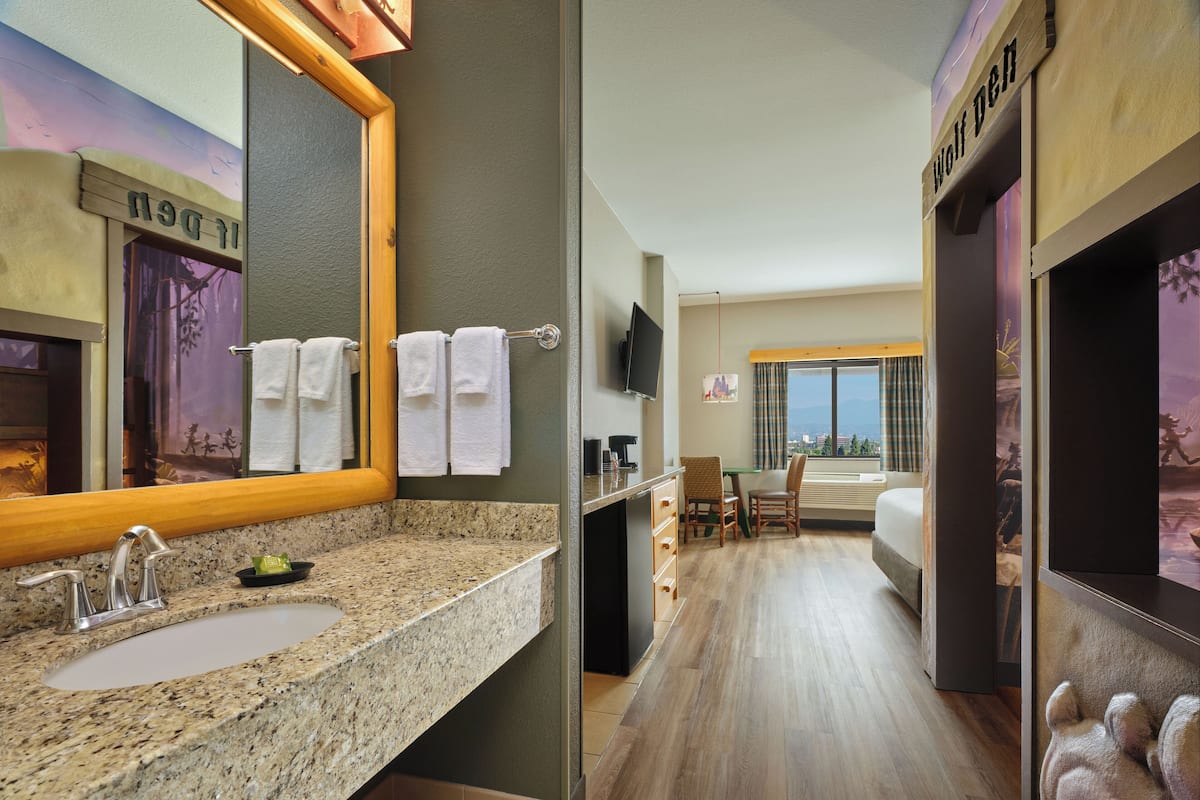 A hotel bathroom with a granite countertop sink, a large mirror, and a towel rack.