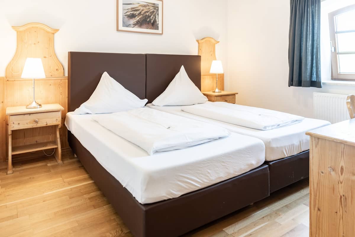 A double bed with white linens, two bedside tables with lamps, and a wooden headboard.