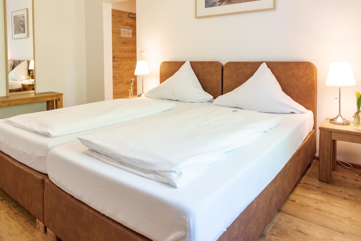 A double bed with white linens and a wooden headboard in a hotel room.