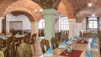 A dining area with brick arches, wooden tables, and chairs.