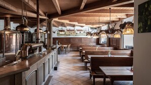 A restaurant with wooden beams, tiled floor, and multiple seating areas including booths and tables. - Brauereigasthof Stanglbräu (Hausen)