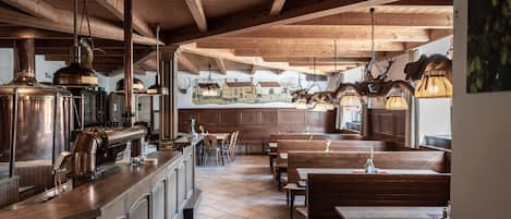 A restaurant with wooden beams, tiled floor, and multiple seating areas including booths and tables.