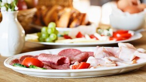 A table with plates of sliced meats, vegetables, and bread. - Brauereigasthof Stanglbräu (Hausen)