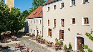 A hotel courtyard with outdoor seating, a church tower, and a cobblestone path. - Brauereigasthof Stanglbräu (Hausen)