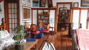 Een klassieke kamer met houten vloer, een zithoek met tafel en stoelen, een boekenplank en een waterdispenser.