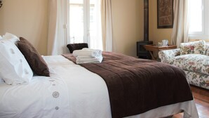 Een hotelkamer met een bed, een stoel, een tafel, een open haard en een bank.
