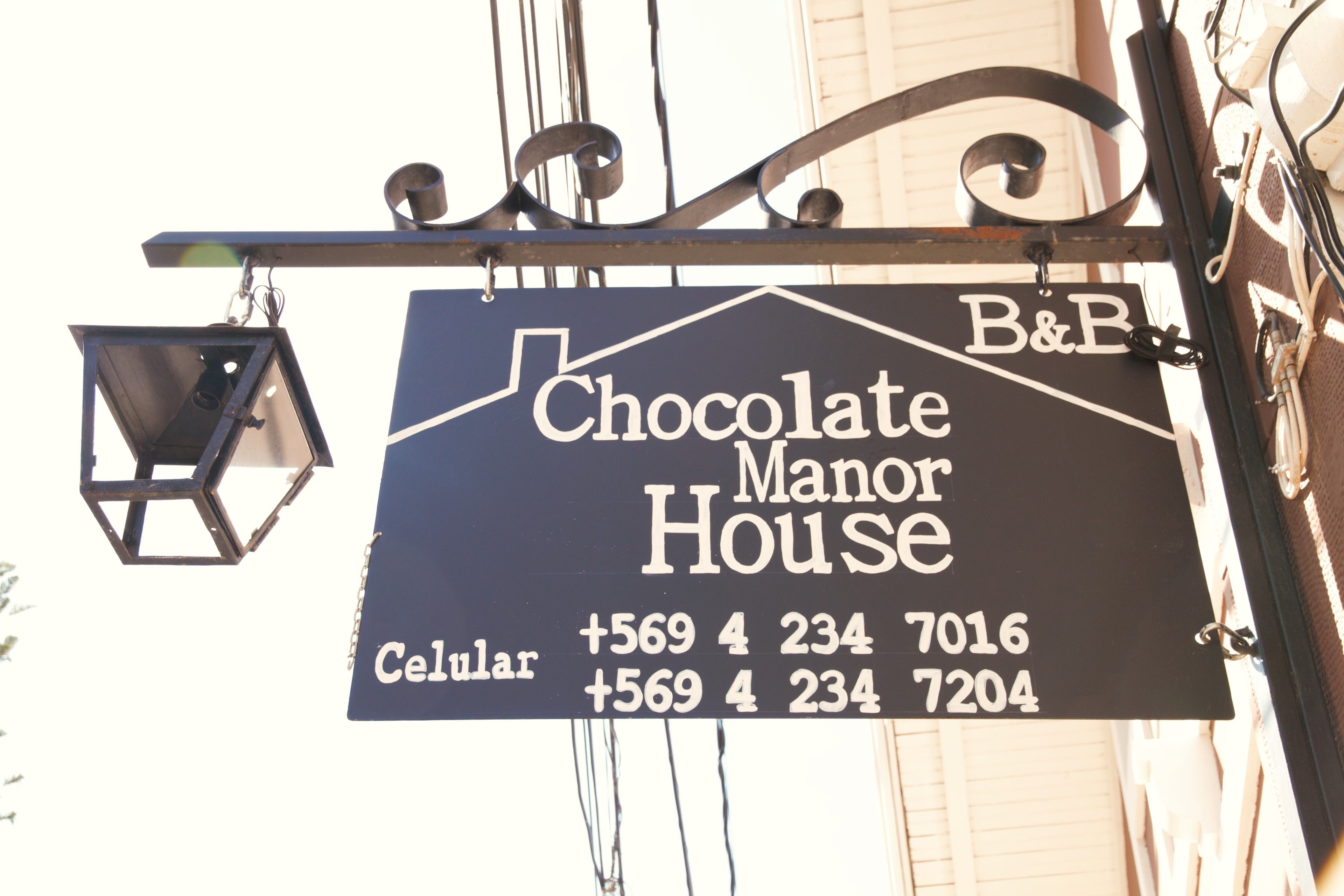 A sign for Chocolate Manor House with two phone numbers.