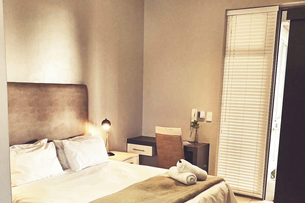 Ein Hotelzimmer mit einem großen Bett, Nachttischen, einem Schreibtisch und einem Stuhl.