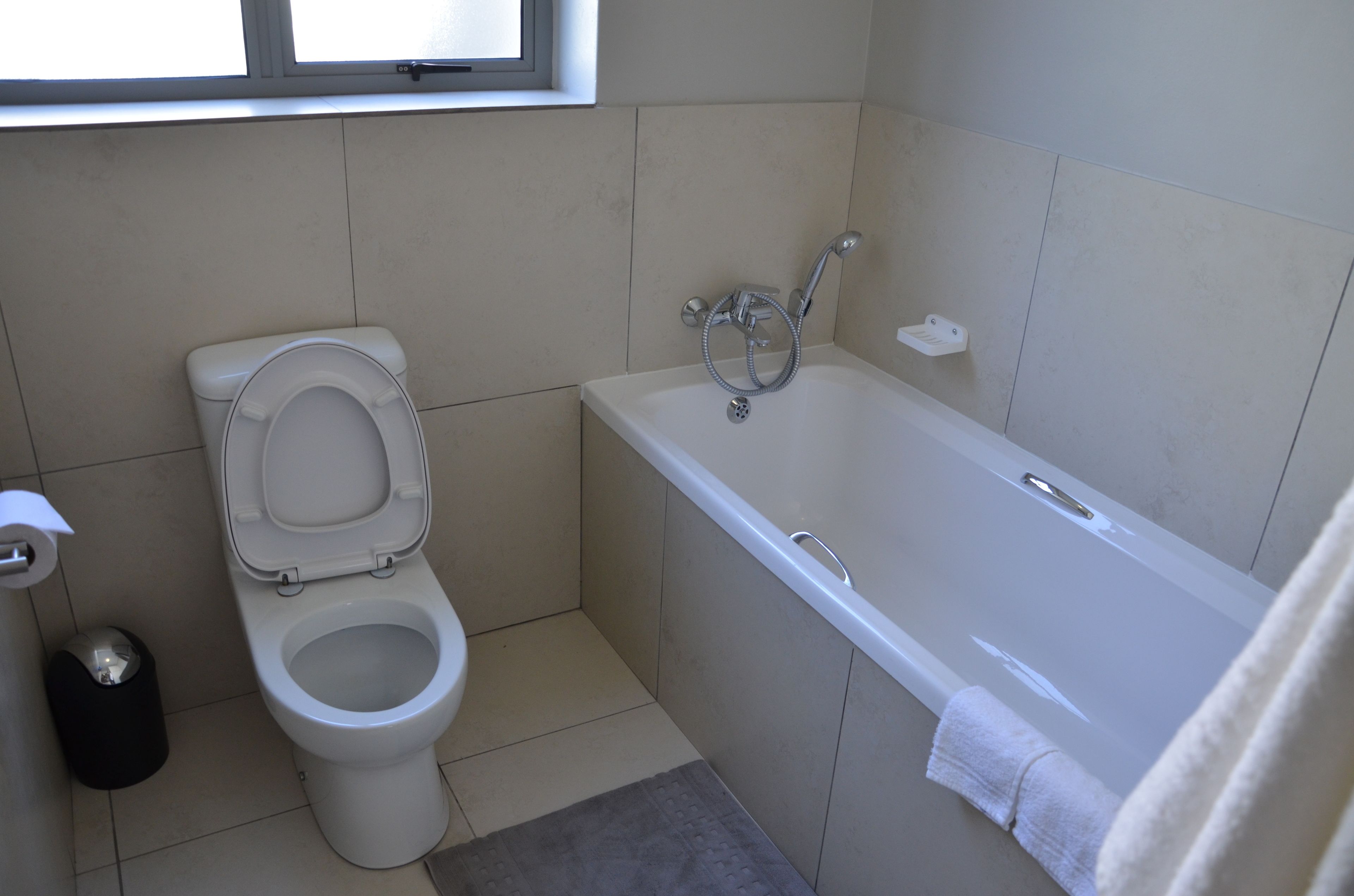 A bathroom with a toilet, a bathtub, and a window.