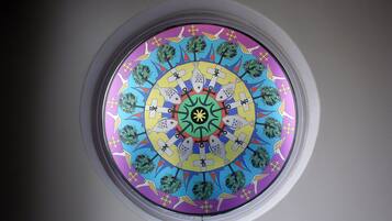 A circular stained glass window with a symmetrical design featuring fish, trees, and geometric patterns.