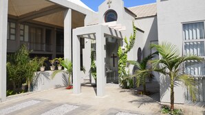 A courtyard with a covered seating area, a small altar, and potted plants. - Be Still Accommodation (Swakopmund)