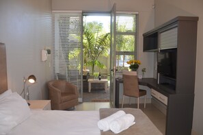 Habitación de hotel con cama, dos sillones, un escritorio, televisor y vistas al exterior.