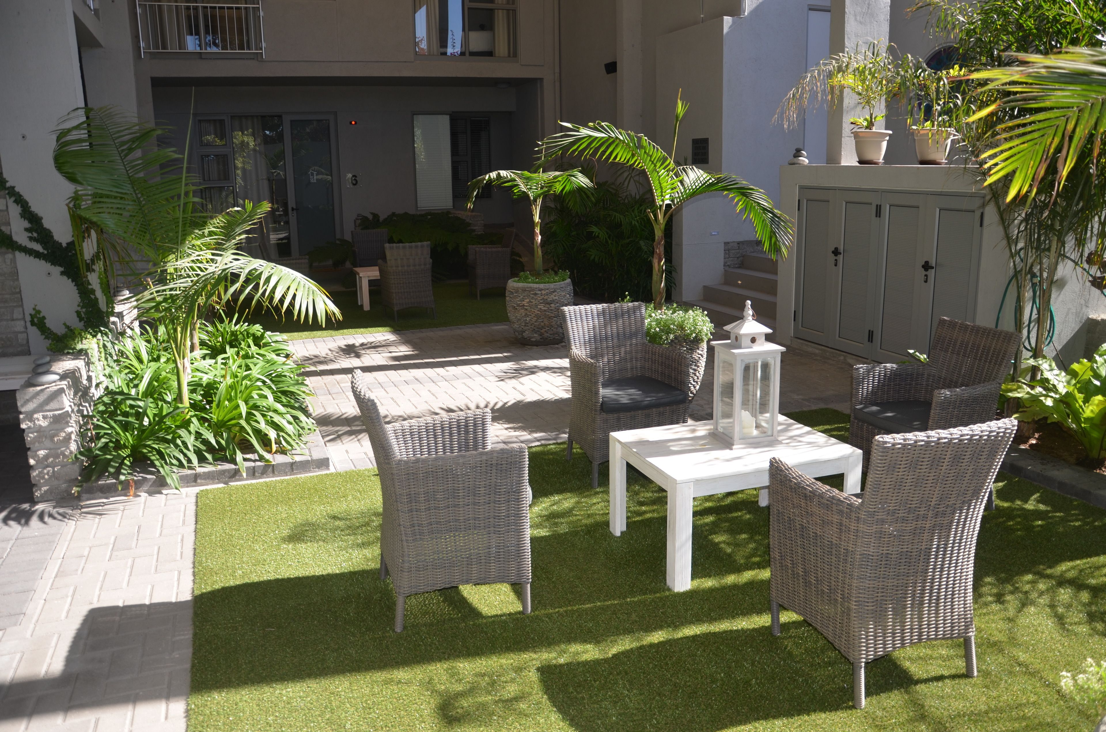 An outdoor patio area with wicker furniture, a white table, and potted plants.