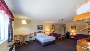 Habitación de hotel con cama, escritorio, sillón, sofá, mesa y calefactor.