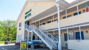 Un motel con un porche cubierto y una escalera que lleva a la entrada.